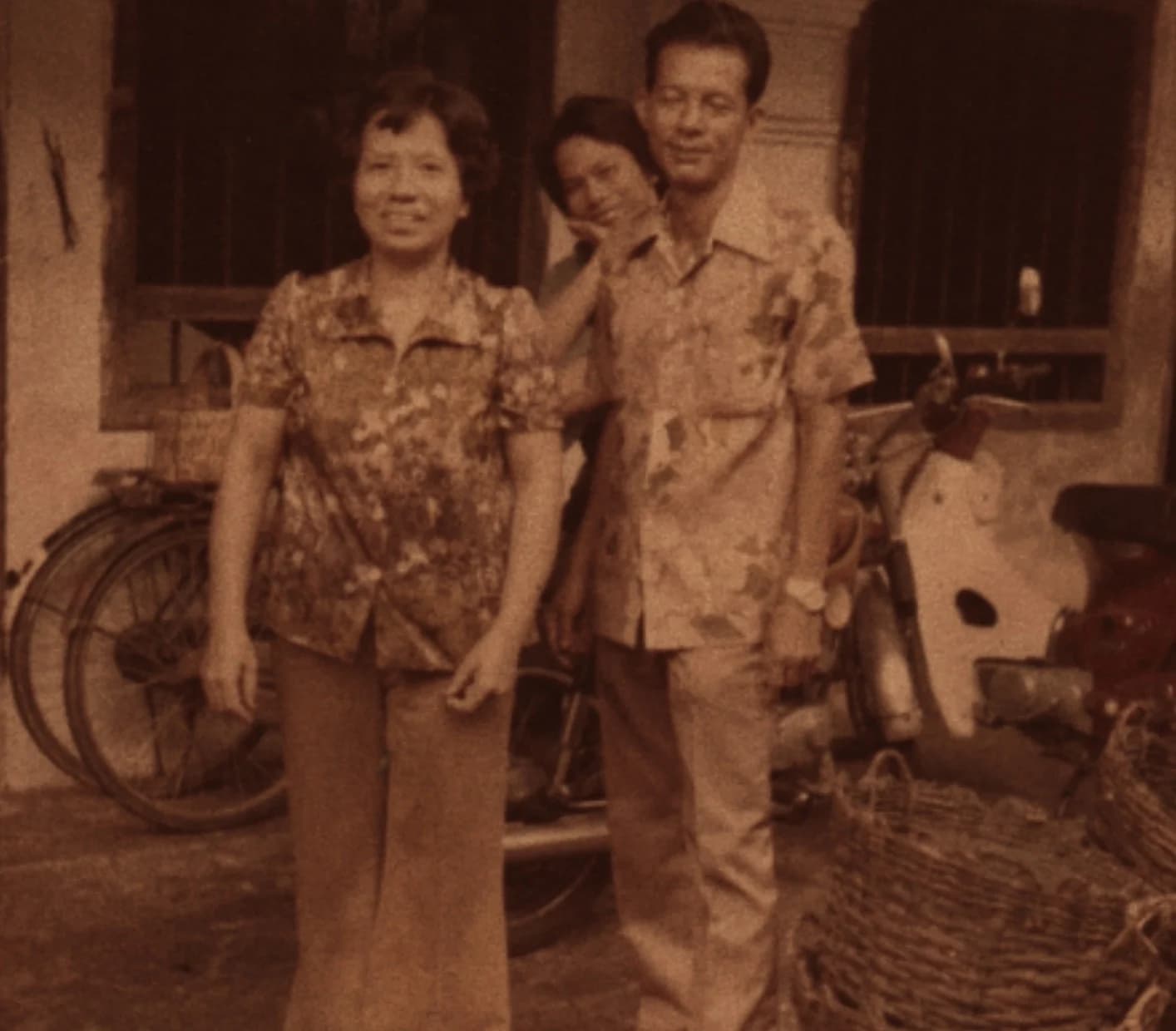 Archival family photograph of the Methee family outside their Phuket shophouse with a woven cashew basket