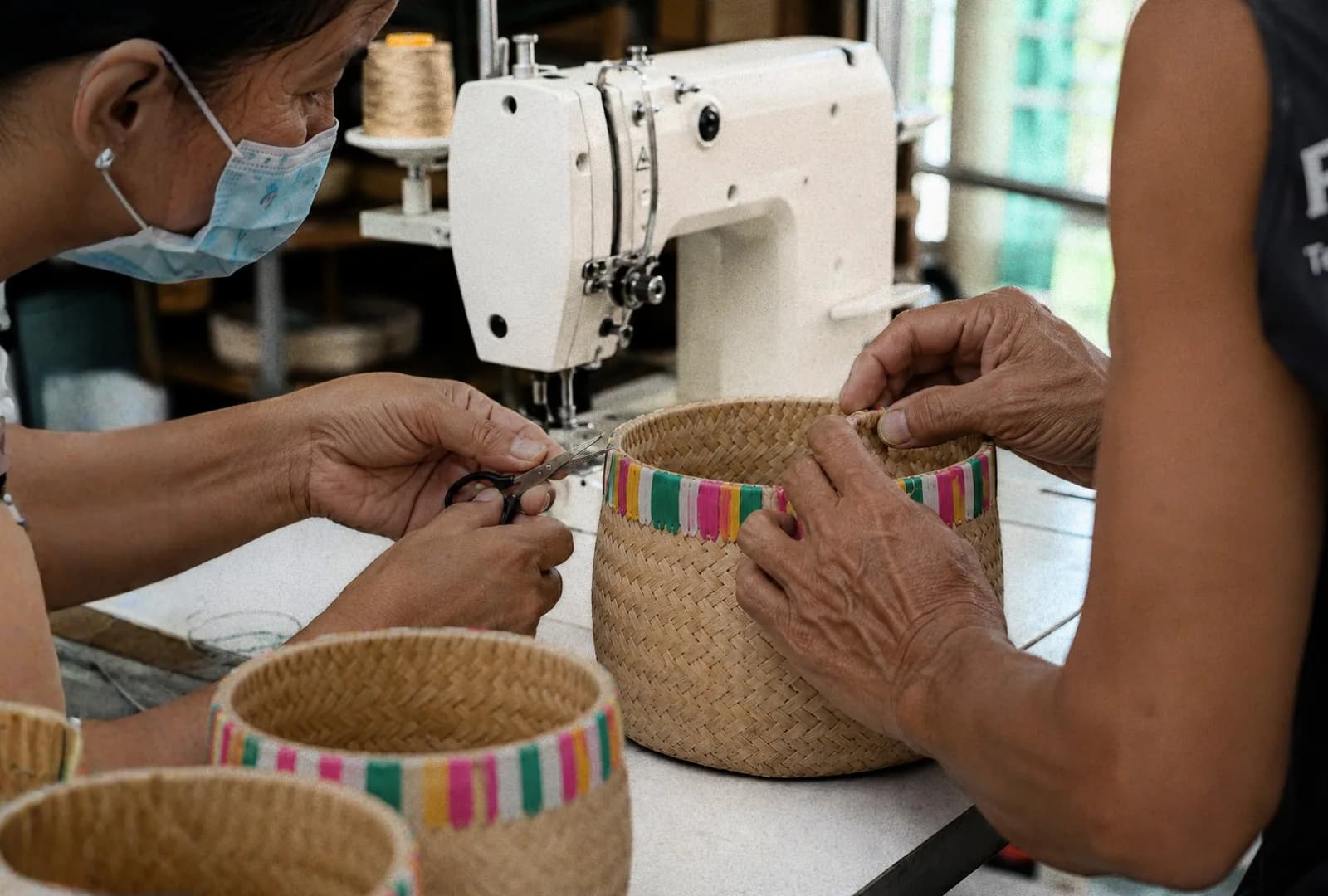 Two makers stitching a woven basket at a sewing machine in the workshop